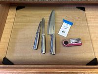 Set of three Farberware cutting utensils and a Farberware sharpener displayed on a wooden cutting board.