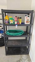 Front view of plastic storage shelving with bottles and garden hose on shelves.