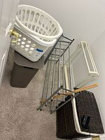 Photo of the lot showing laundry hampers, shoe racks, boot helpers and alarm clock against a white wall on carpeted floor.