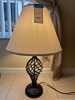 Table lamp with cream pleated shade and black twisted metal base, turned on showing working condition