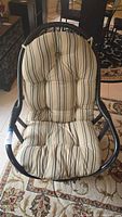 Front view of leisure swivel chair with beige and black striped fabric cushion on black curved frame.