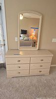 Full front view of light wood six-drawer dresser with matching mirror above, showing brass-tone drawer pulls and wood grain finish.