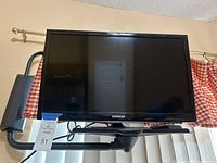 Samsung 22-inch TV showing front screen and stand in front of a window with curtains.