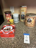 Six assorted vintage decorative tin cans including Cafe, Pure Cane Sugar, Seasoning, Spaghetti, Pasta, and Potato Chips