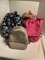 Three backpacks: black sequin, pink fabric, beige faux leather