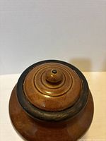 Top view of brown ceramic lid with knob finial and dark rim accent