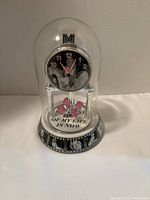 Front view showing glass dome, dial, pendulum and base graphics