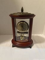 Front view of cylindrical cherrywood mantel clock showing brass-tone dial and glass panels
