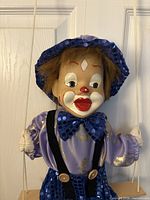 Close-up of clown marionette head, hat, upper costume on swing