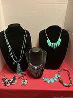 Group of seven necklaces displayed on stands and laid flat