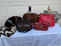 Group shot of all seven handbags on table