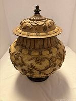 Front view showing bowl on pedestal with lid and ornate relief