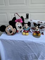 Group shot showing all five items: Minnie plush basket, Mickey head plush, small Mickey plush, figurine, boxed cake pop maker