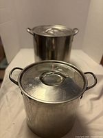 Two aluminum stock pots with lids, front and back view