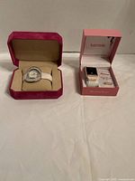 Both watch boxes side by side showing Peugeot watch in pink box and unopened Kensie watch set