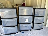 Three Sterilite plastic drawer units shown side by side on white surface in indoor setting. Each unit has 3 clear drawers and black frames, two units have wheels at bottom.