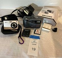 Both cameras, Bi-Direction switch, charging cords, camera cases, memory card, instruction manual, all laid out on a table.