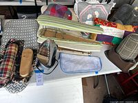 Electric iron, three small ironing boards, and handmade pillows arranged on a table.