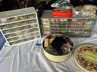 Photo of two plastic multi-compartment organizers filled with assorted buttons, and two round storage tins containing sewing notions.
