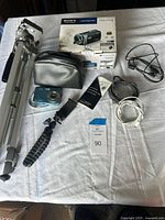 Sony Handycam HDR-CX190 video camera box, tripod, carrying case, charger, cables, and Kodak digital camera on white cloth.