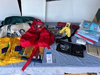 Overview photo showing all items laid out including backpacks, ponchos, stuffed animals, bags, and calendar.