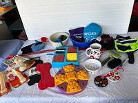 Overview photo of various dog supplies including lick mats, unopened Nylabones, bowls, treat trays, brushes, a leash, and decorative items.