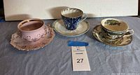 Three ceramic teacup and saucer sets arranged on a surface, showing the full lot