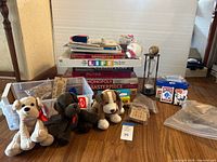Overview image of lot showing board games stacked with plush animals in front, playing cards, hourglass timer, and other game pieces.