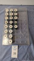 Top-down photo showing 21 spools of Gutermann thread arranged in 3 columns with varying shades of green in clear plastic tray with lid closed.