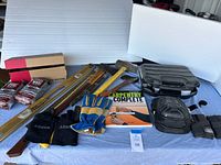 Wide view showing assortment of tools on blue cloth including axe, level, gloves, socket set, knee pads, books, and steel wool.