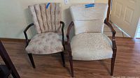 Photo of two mismatched vintage traditional upholstered armchairs side by side, showing overall condition and details of fabric and wood frame.
