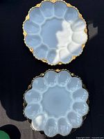 Two matching milk glass platters with gold rims