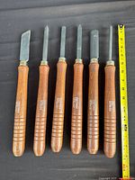 Six chisels laid out with tape measure for scale