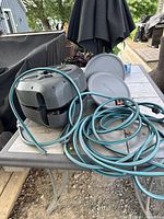 Overall view of disassembled Gardena hose reel with housing, side covers and hose on table