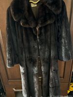 Front view of full-length dark brown mink coat on hanger