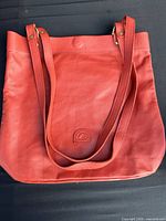 Front view of red leather messenger bag showing shape and straps