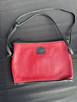 Front view of red leather purse with black strap and trim