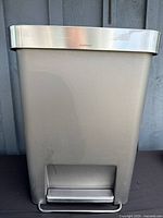 Front view of simplehuman grey step trash can showing foot pedal and stainless rim