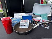 Group shot of all items including Android box, frying pan, travel mug, hose, test kit, coasters and magnetic bar