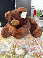 Front view of large brown plush bear with tag