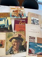 Top view of assorted vinyl albums stacked showing varied album art including John Denver Greatest and Victor & Esther albums