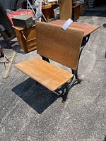 Front angled view showing wooden writing surface, attached seat and backrest, and iron base structure.