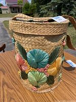 Front view of the handmade Bahamas woven basket tote showing colorful embroidered flowers in teal, yellow, peach, and green.