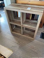 Front view of barnwood look bookshelf with four cubbies showing wood grain finish and square compartments.