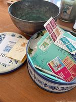 Photo of copper bowl and round tin with postage stamps, envelopes, and booklets