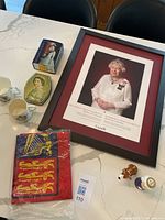 Framed portrait and memorabilia items on a table including tins, mugs, flag, and salt and pepper shakers
