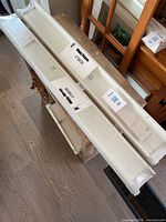 Two white IKEA wall display shelves on floor, still with original packaging and instructions, showing length and profile.