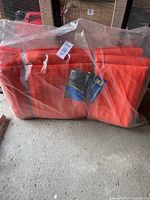 Full view of the folded orange insulated tarp inside a plastic bag on the floor.