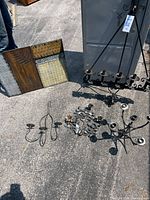 Photo showing all five pieces including metal panel artwork, iron chandelier, candelabra, and two sconces arranged on pavement.
