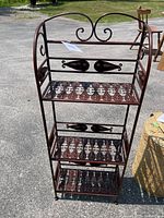 Full view of the metal accent shelf showing the overall structure with three tiers and scroll designs on sides and back.